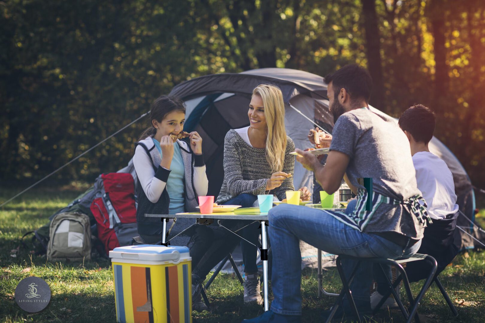 A group of people sitting around a table in the grass.