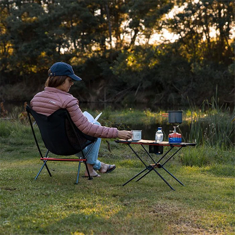 A woman sitting in an outdoor chair with a table and chairs.