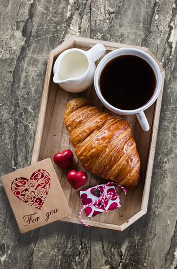 A tray with croissant, coffee and a card.