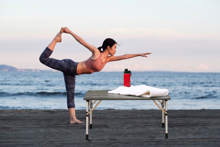 A woman is doing yoga on the beach