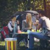 A group of people sitting around a table in the grass.