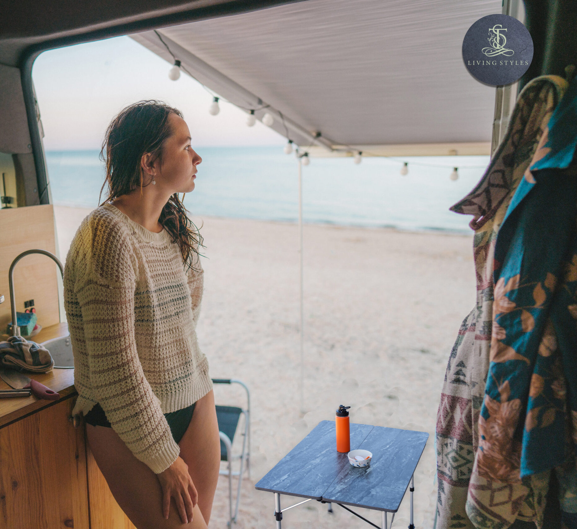 A woman standing in front of an open window on the beach.