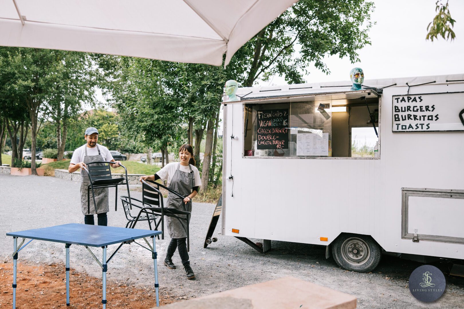 A couple of people standing next to a food truck.